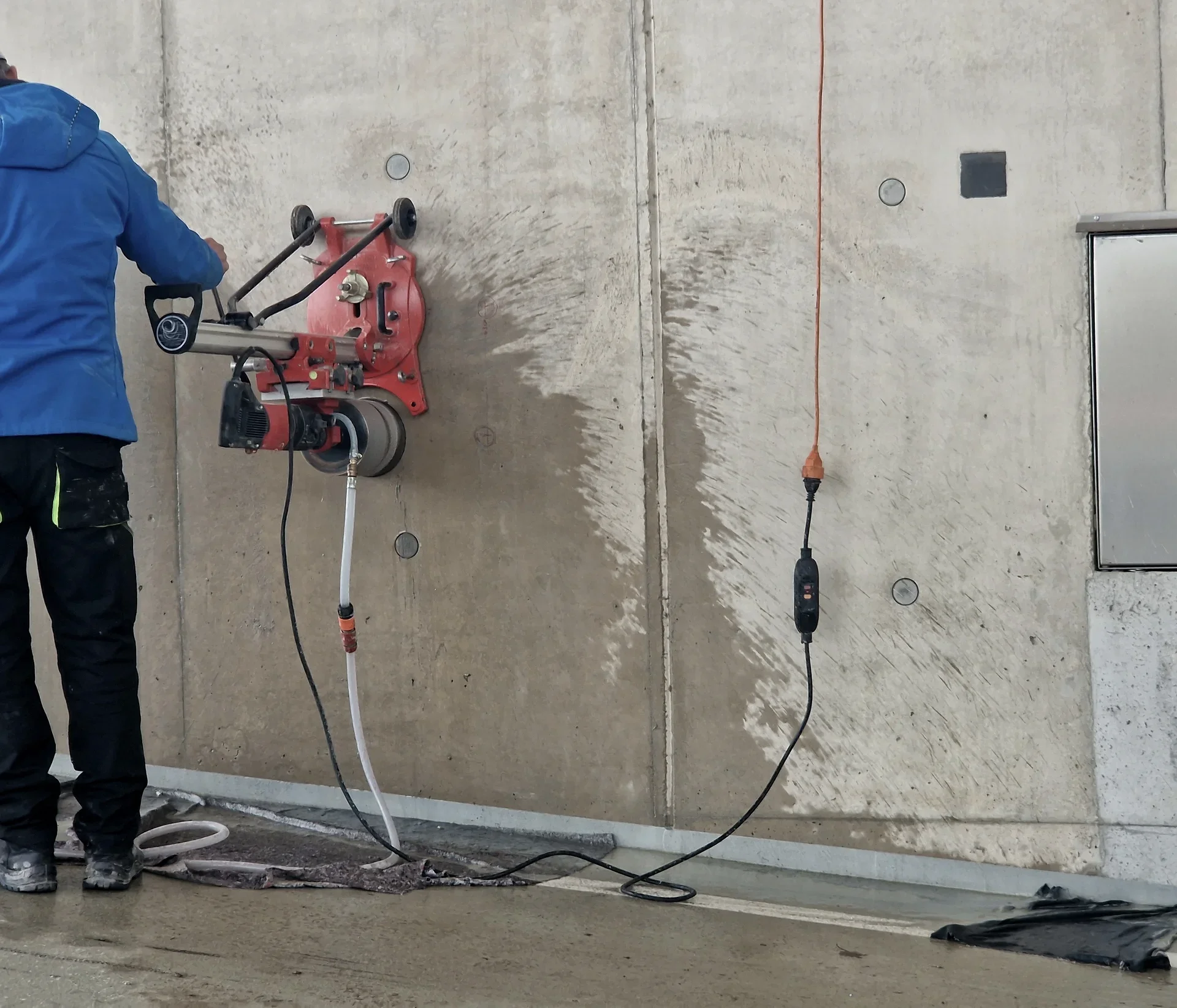 Arbetare använder vattenkyld kapmaskin mot betongvägg med elkabel