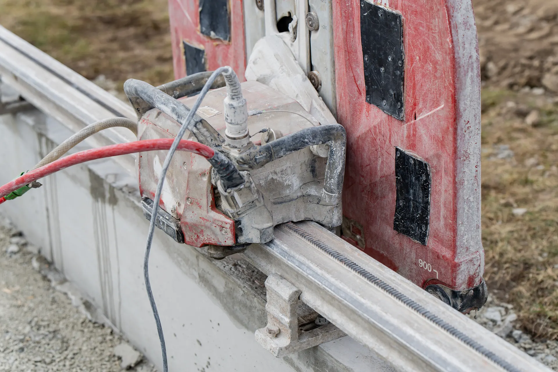 Dammigt elverktyg monterat på skena vid betongkant utomhus.