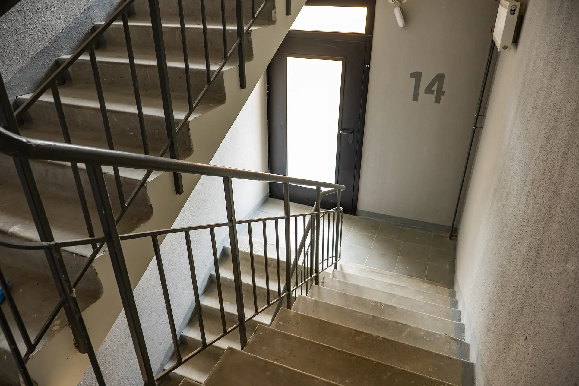 Trapphus i flerbostadshus med metallräcke och dörr märkt nummer 14.